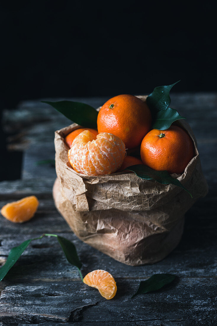 Clementines in a paper bag, one peeled