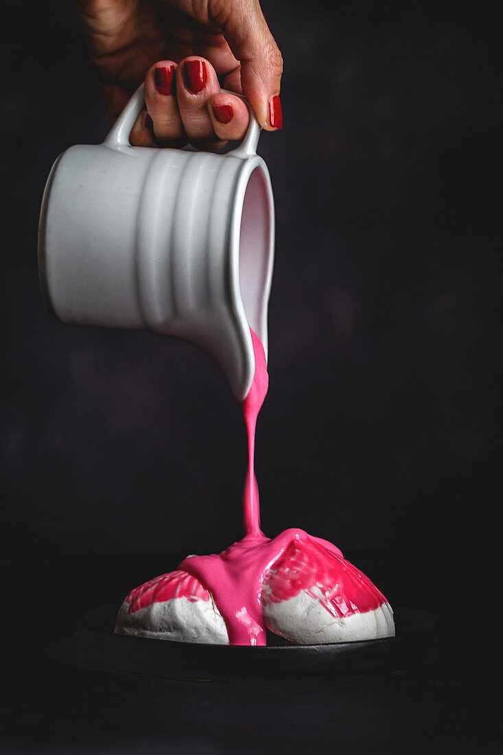 Woman pouring pink strawberry syrup on homemade white Zefir traditional (Russian dessert with mint)