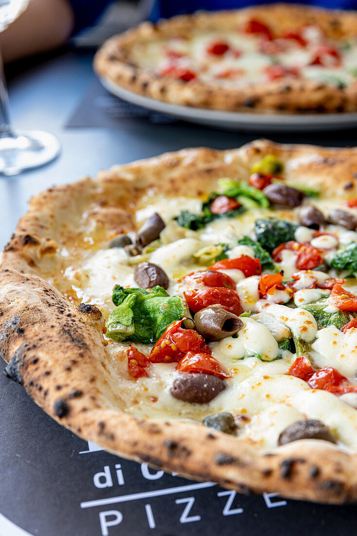 A pizza topped with tomatoes, olives and chicory