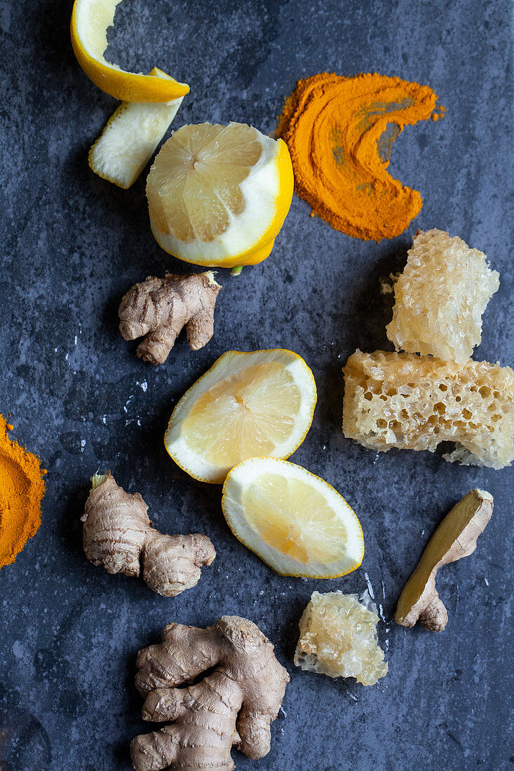Lemon, turmeric powder, ginger, and honeycomb on a blue surface