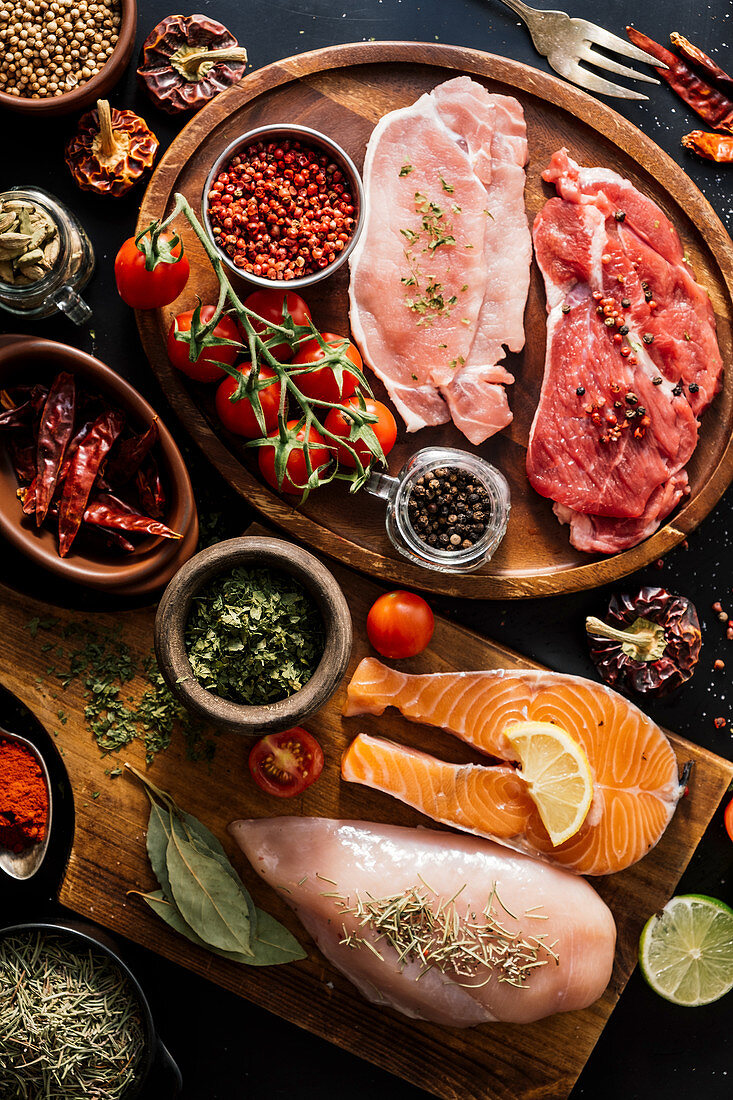 Flat lay of proteins surrounded by spices and seasonings on table