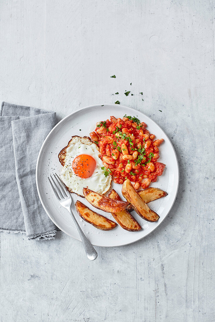 Fried egg, potato chips and tomato and beans