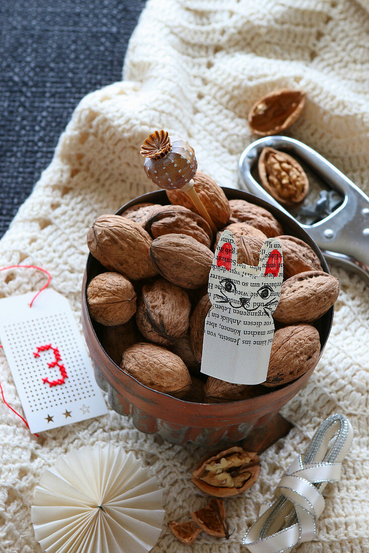 Bowl of nuts and paper cat on woollen blanket