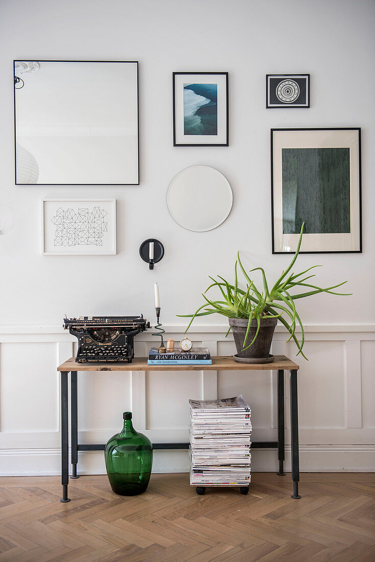 Console table against panelled wall with gallery of pictures