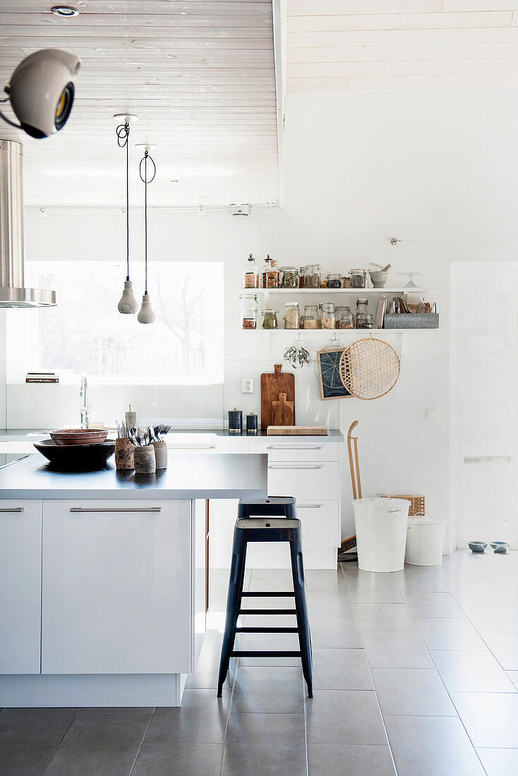 The industrial metal and wood kitchen stools echo the materials and structure used in the bookshelves along one wall of this kitchen