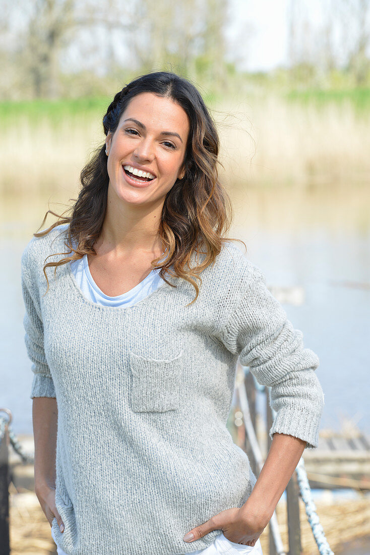 A young woman wearing a grey jumper near river