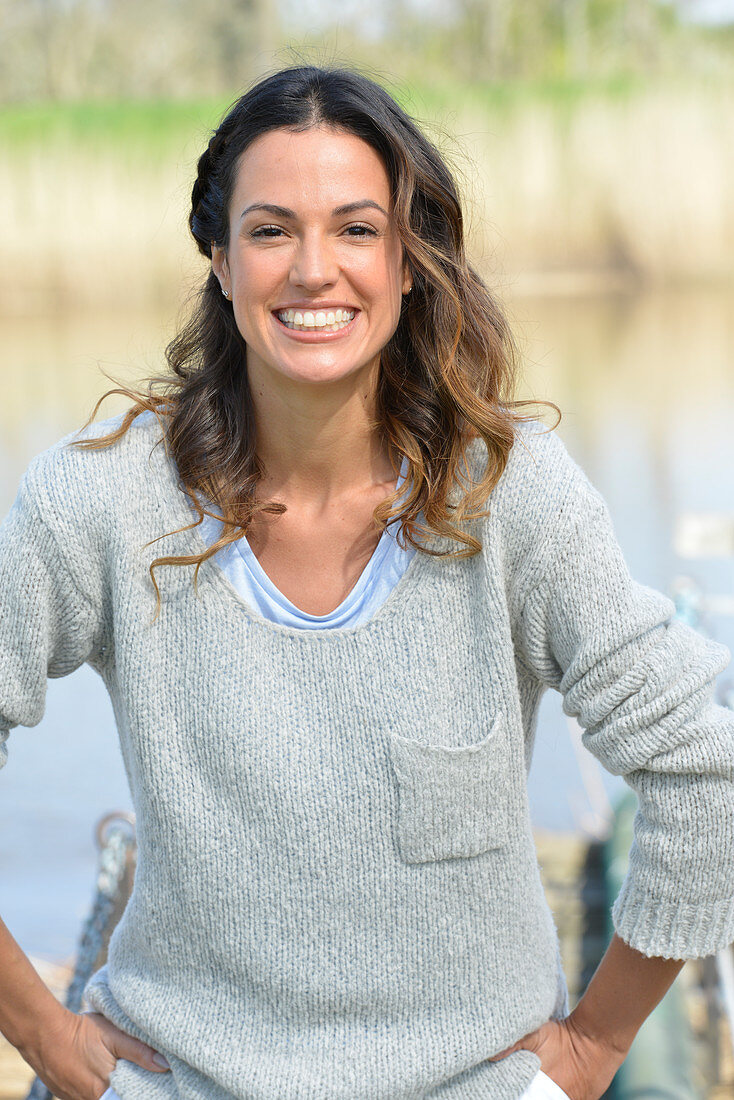 A young woman wearing a grey jumper near river