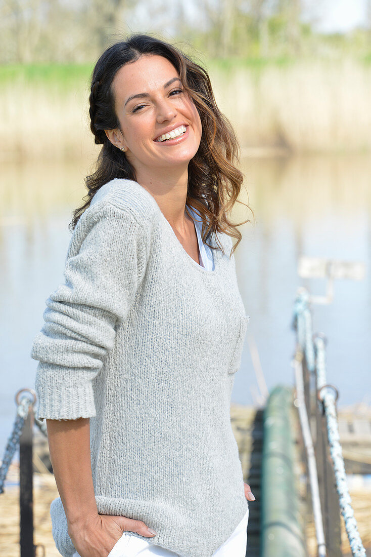 A young woman wearing a grey jumper near river