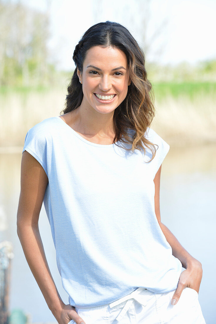 Junge Frau in hellblauem T-Shirt und weißen Shorts am Fluss