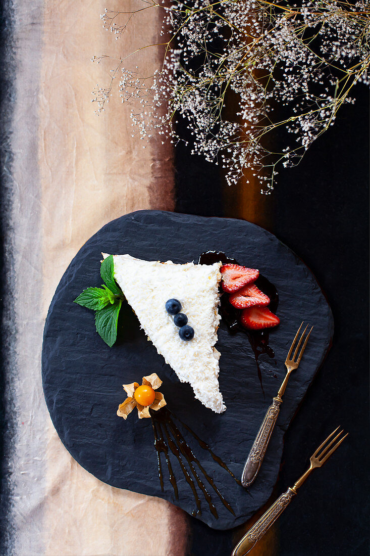 Ein Stück Kokosnusskuchen mit Beeren und Physalis