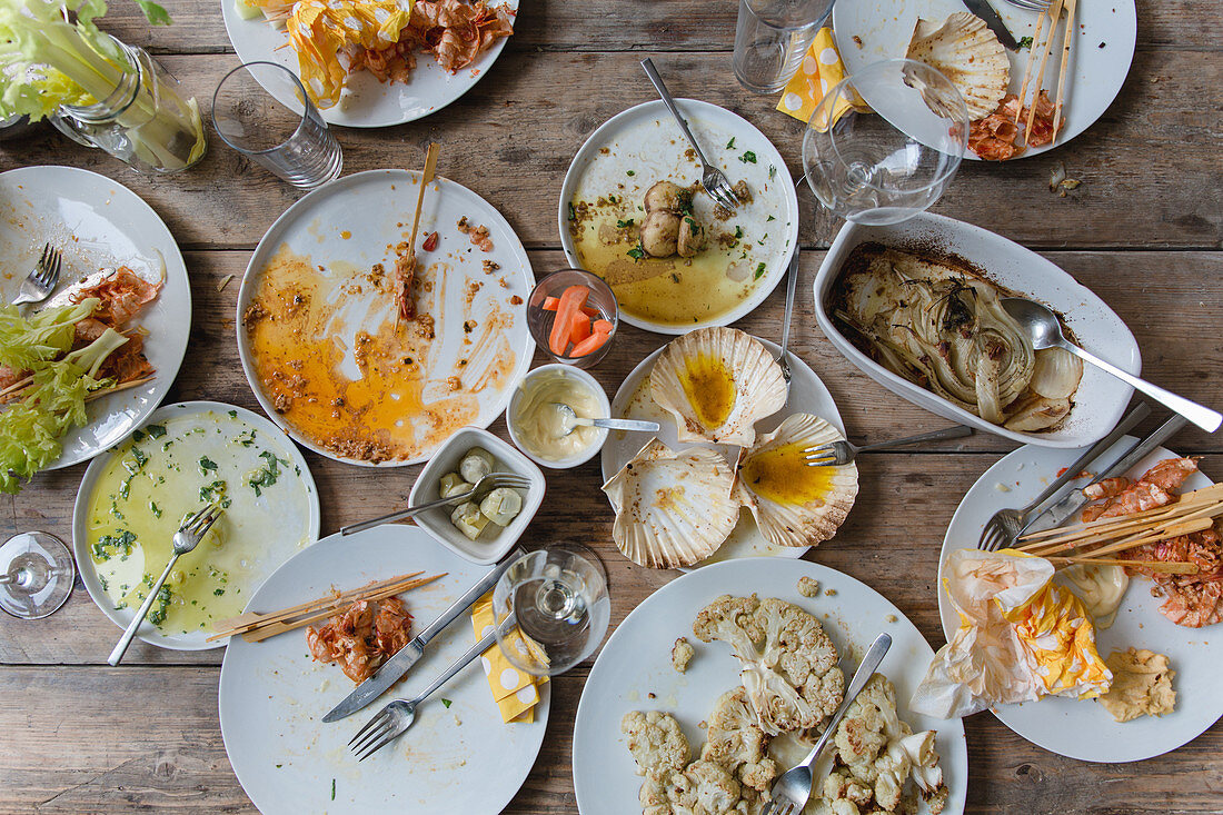 Leftover food and used crockery from a barbecue party