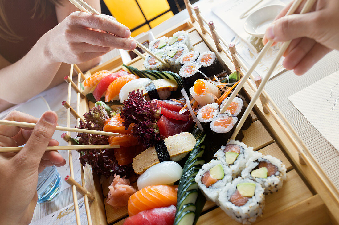 Hands picking up sushi from a japanese restaurant