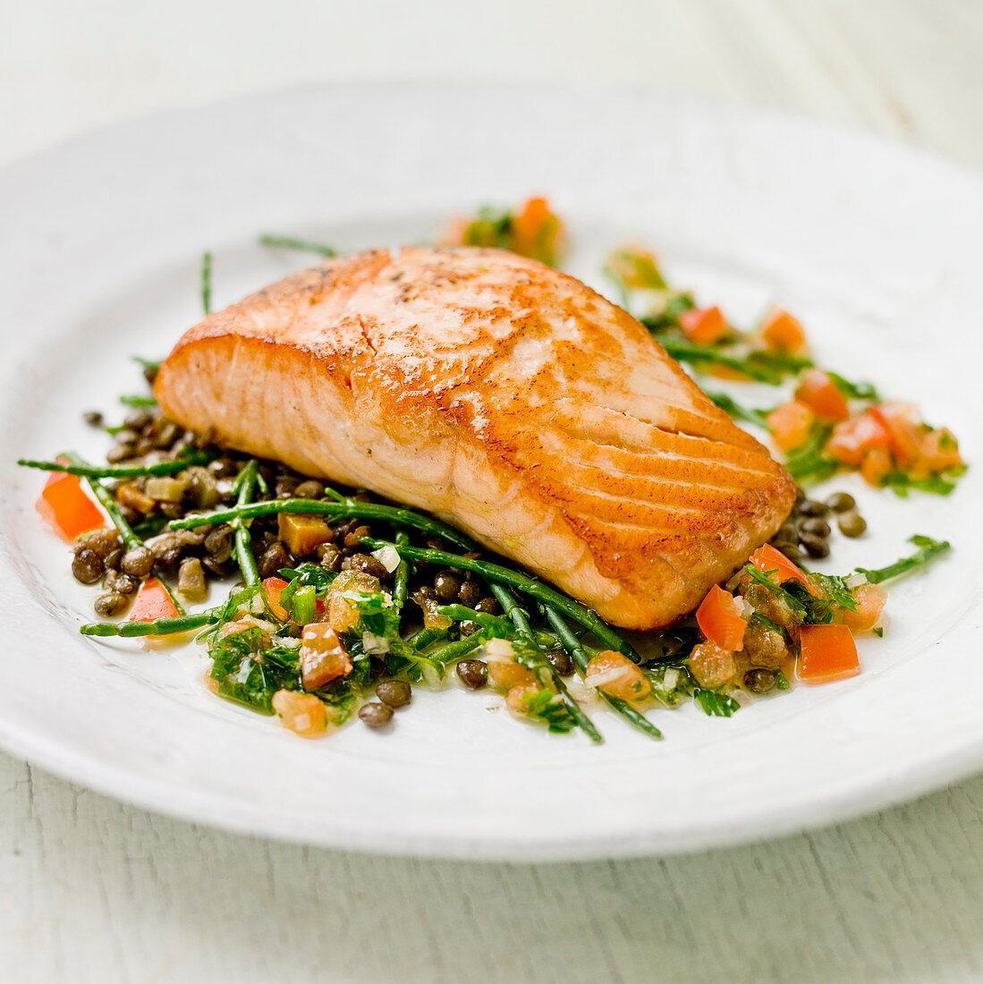 Salmon fillet on a bed of samphire, green lentles and tomatoes with a green herb vinegarette