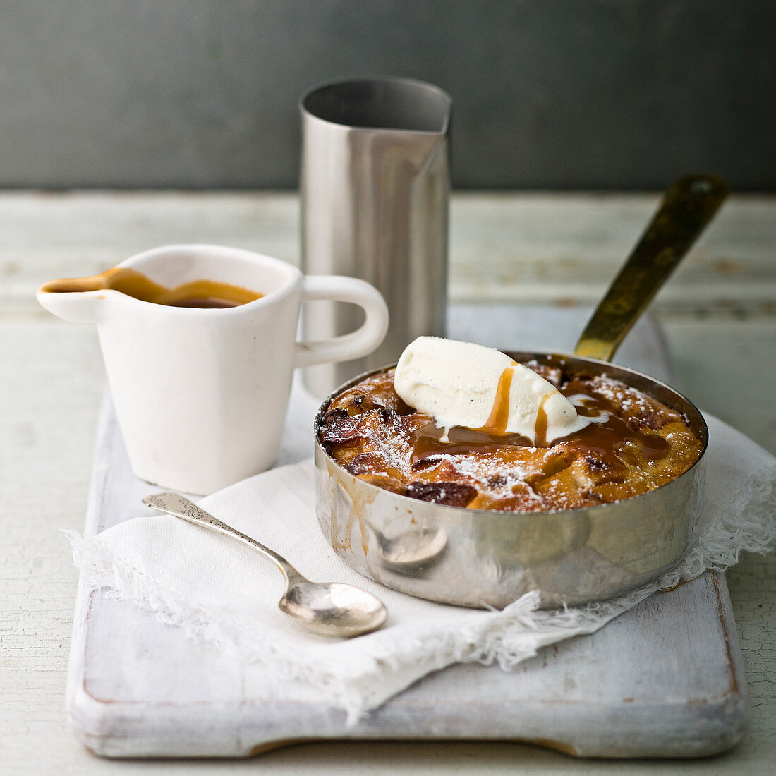 Apple cobbler, with a white jug of toffee sauce with vanilla ice cream