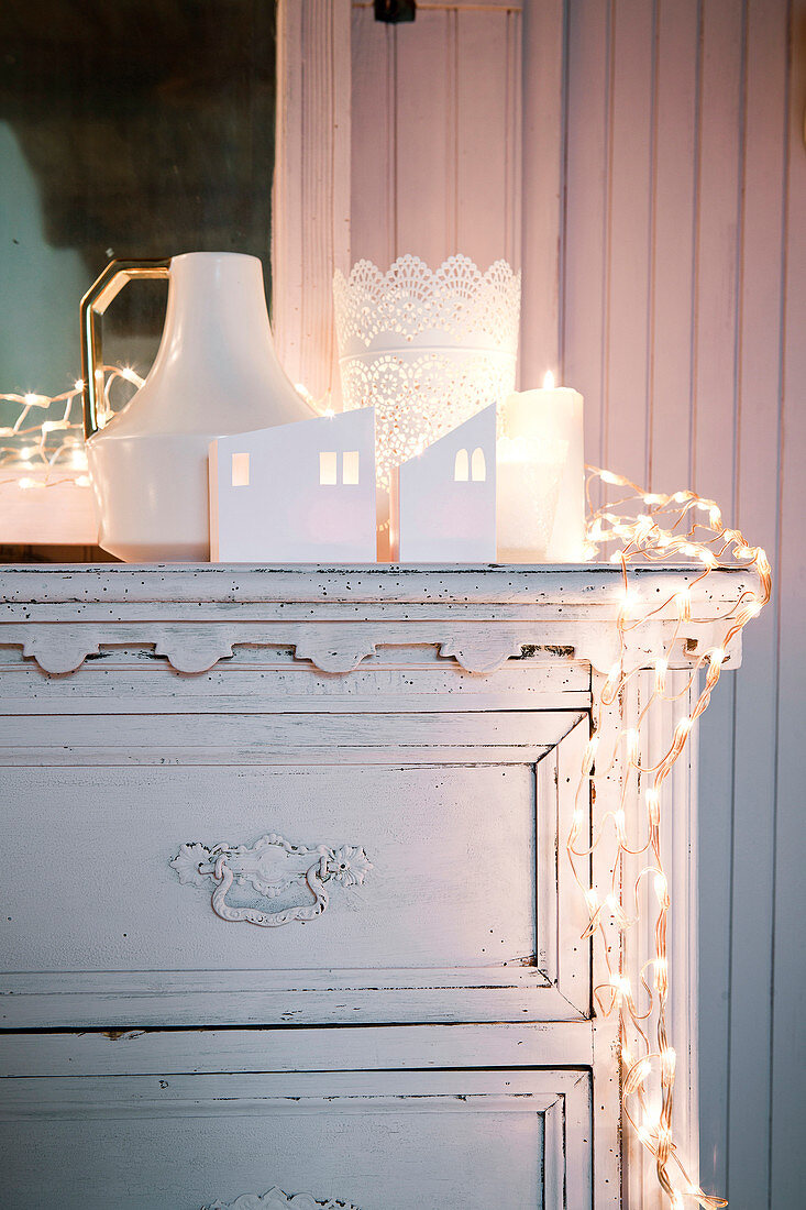 Wintry arrangement of lights in white on top of old chest of drawers