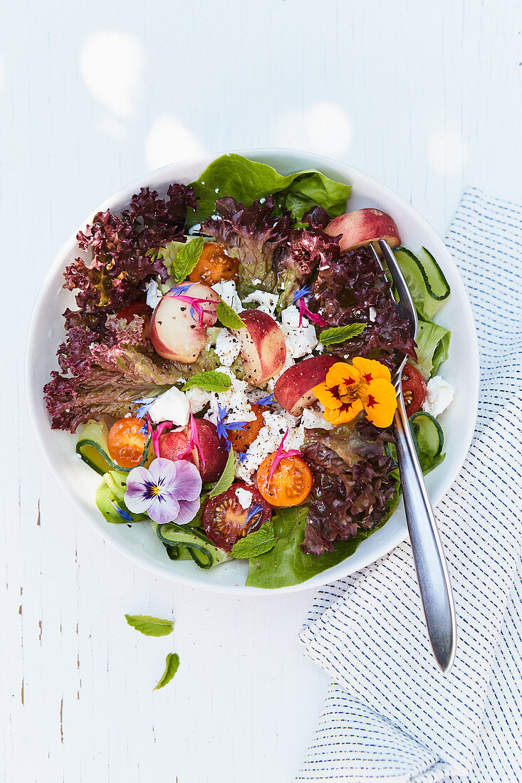A summer salad with nectarines, feta cheese and edible flowers