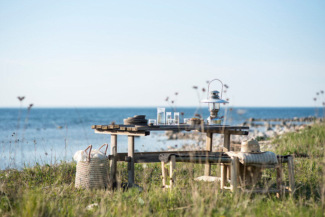 Crockery and lantern on wooden table next to sea