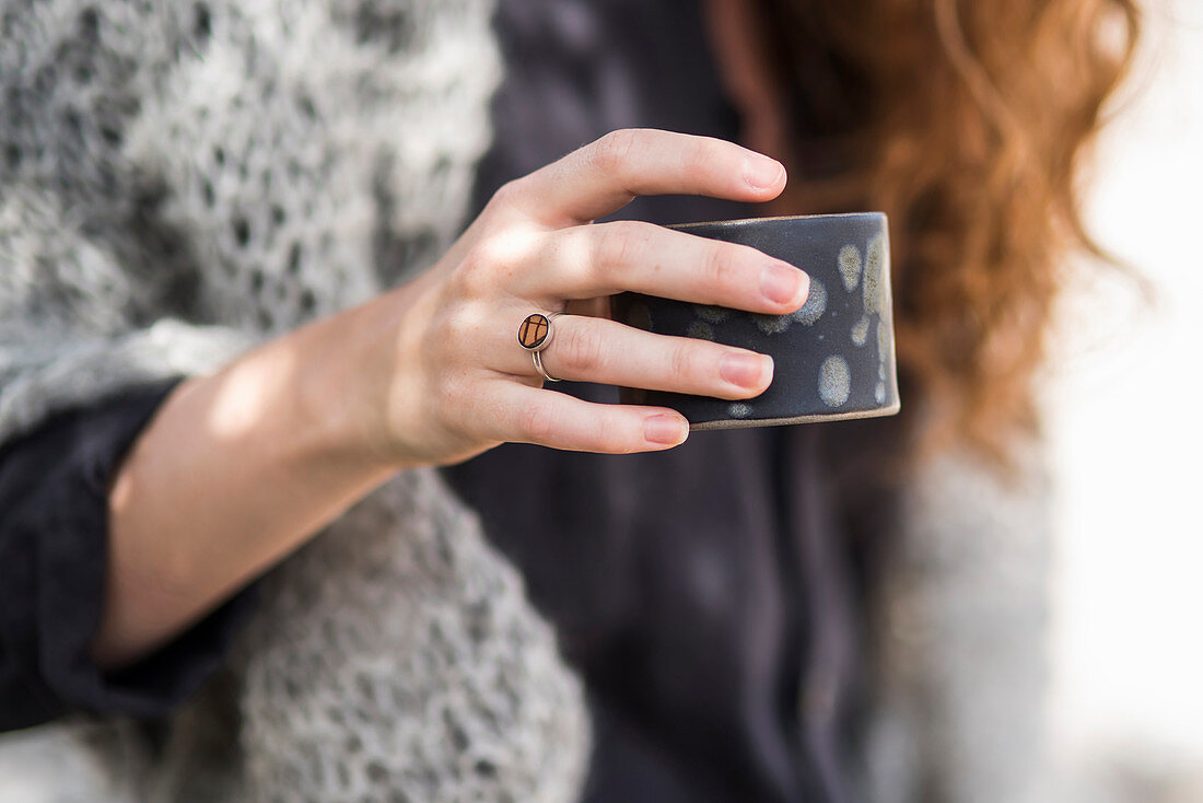 Frauenhand mit Ring hält Becher