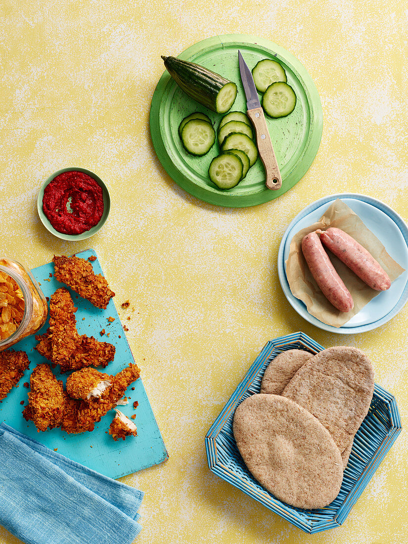 Chicken Nuggets, Fladenbrot, rohe Würstchen und angeschnittene Gurke