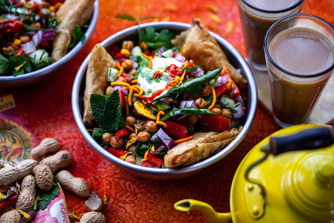 Chaat-Salat (scharfer Kichererbsensalat, Indien) mit Samosas und Erdnüssen