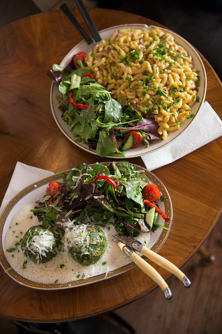 Cheese spätzle (soft egg noodles from Swabia) and spinach dumplings each with a side salad