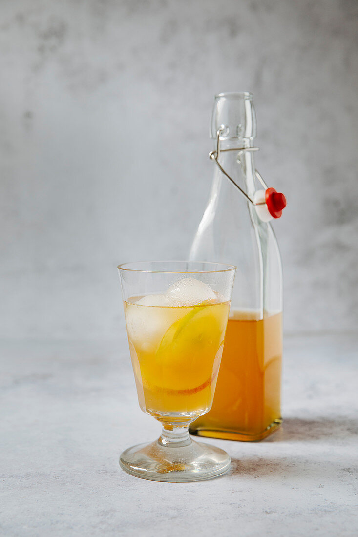 Earl Grey Tee mit Apfelscheiben und Eiswürfeln in Glas und Flasche