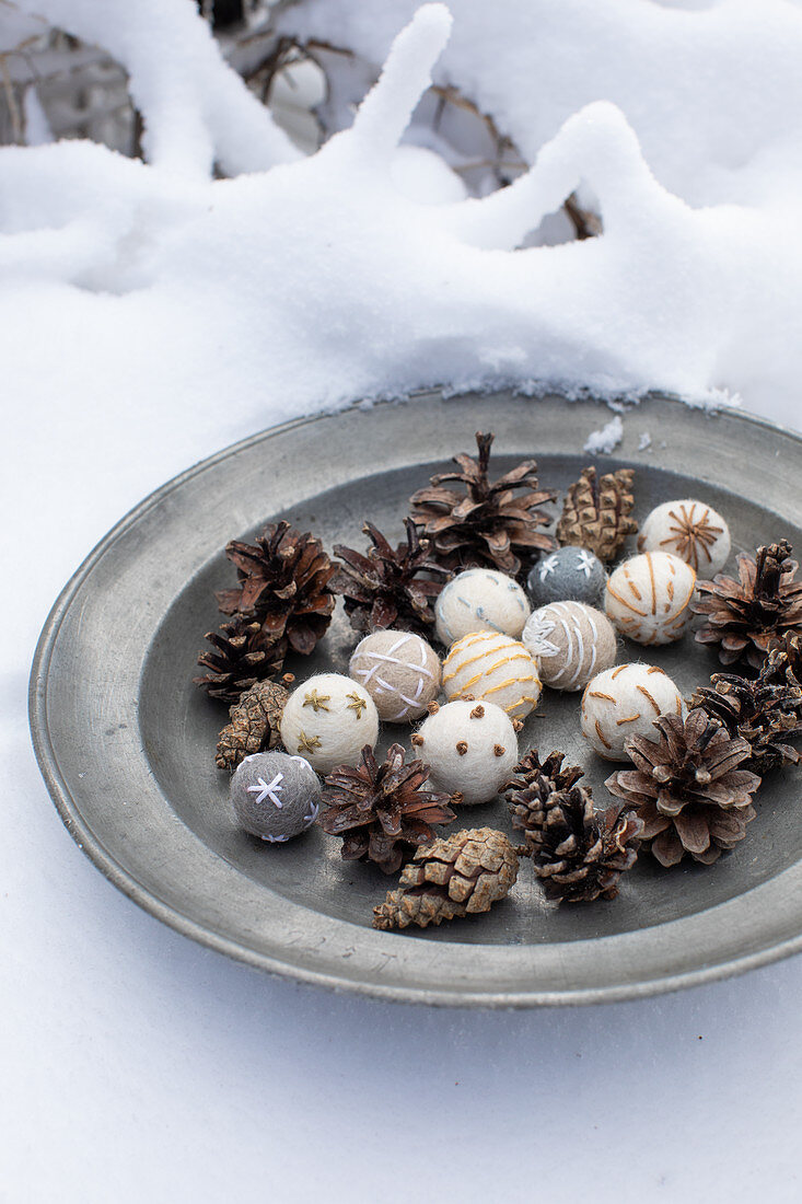 Festive arrangement of embroidered felt balls and pine cones