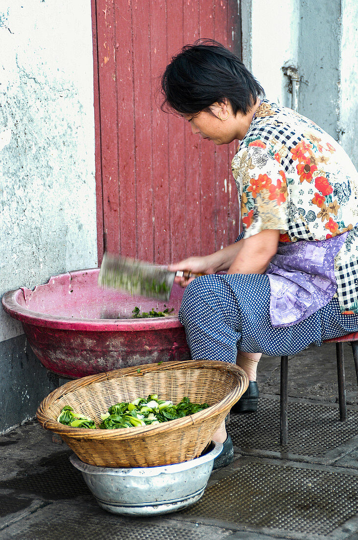 Frau hackt Gemüse auf chinesischem Markt