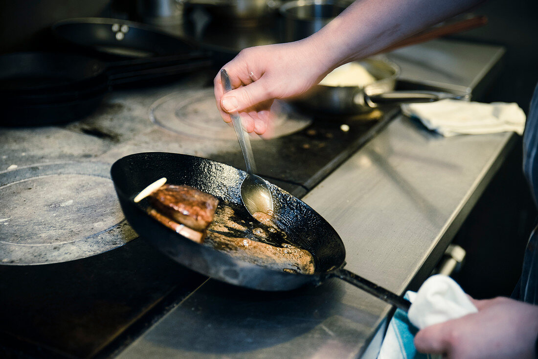 Chef basting Meat in Frying Pan