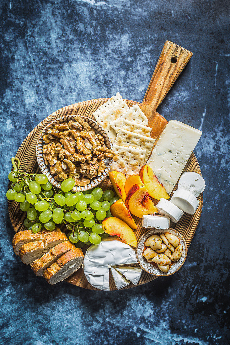 Käsebrett (Ziegenkäse, Brie, Blauschimmelkäse) mit Nüssen, Obst und Brot