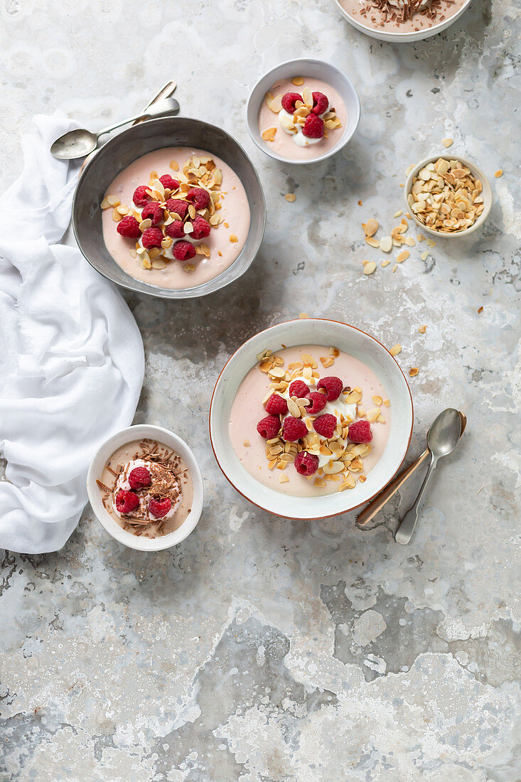 Baked yoghurt dessert in bowls with raspberries and almonds