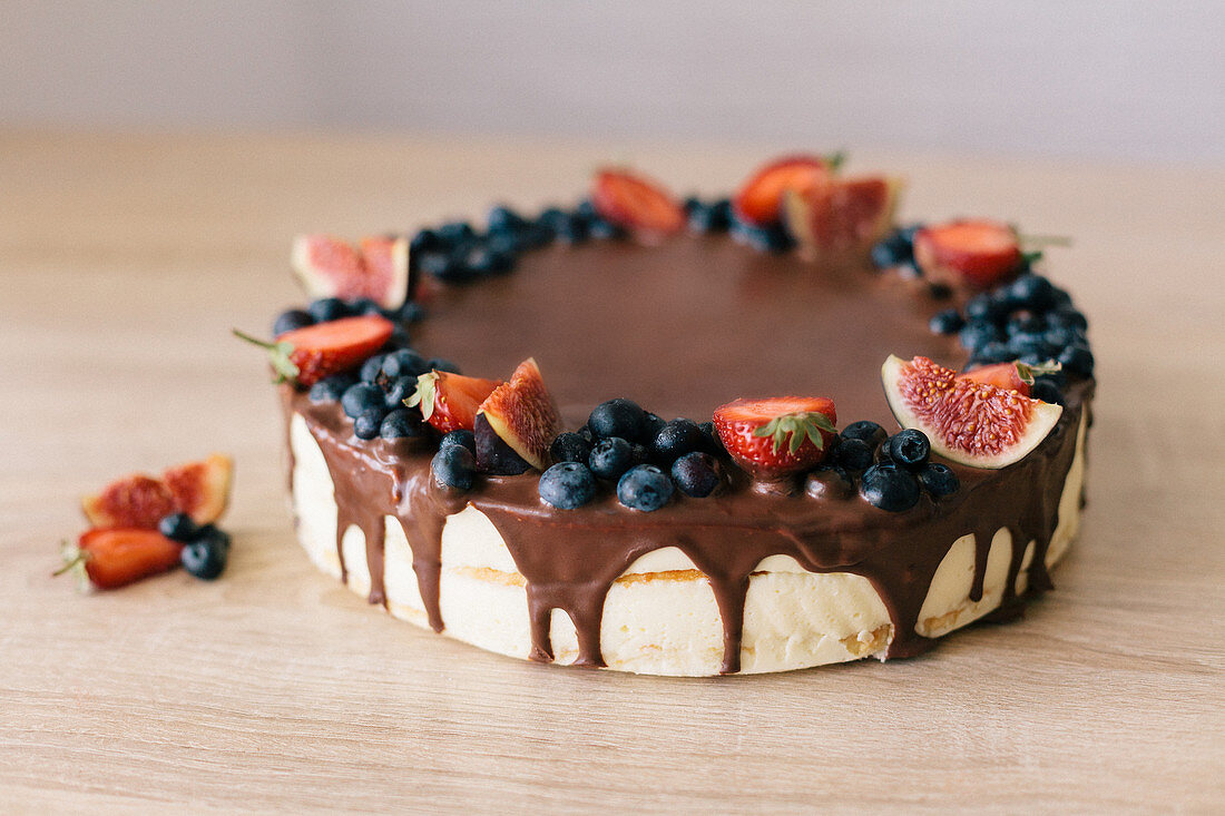 A chocolate drip cake with berries and figs