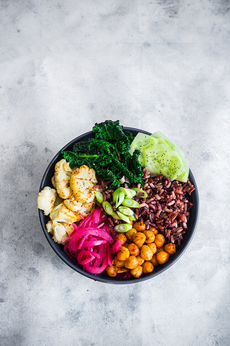 Vegan bowl with wild rice, chilli chickpeas, kale, roasted cauliflower, cucumber, pickled onions and green onions