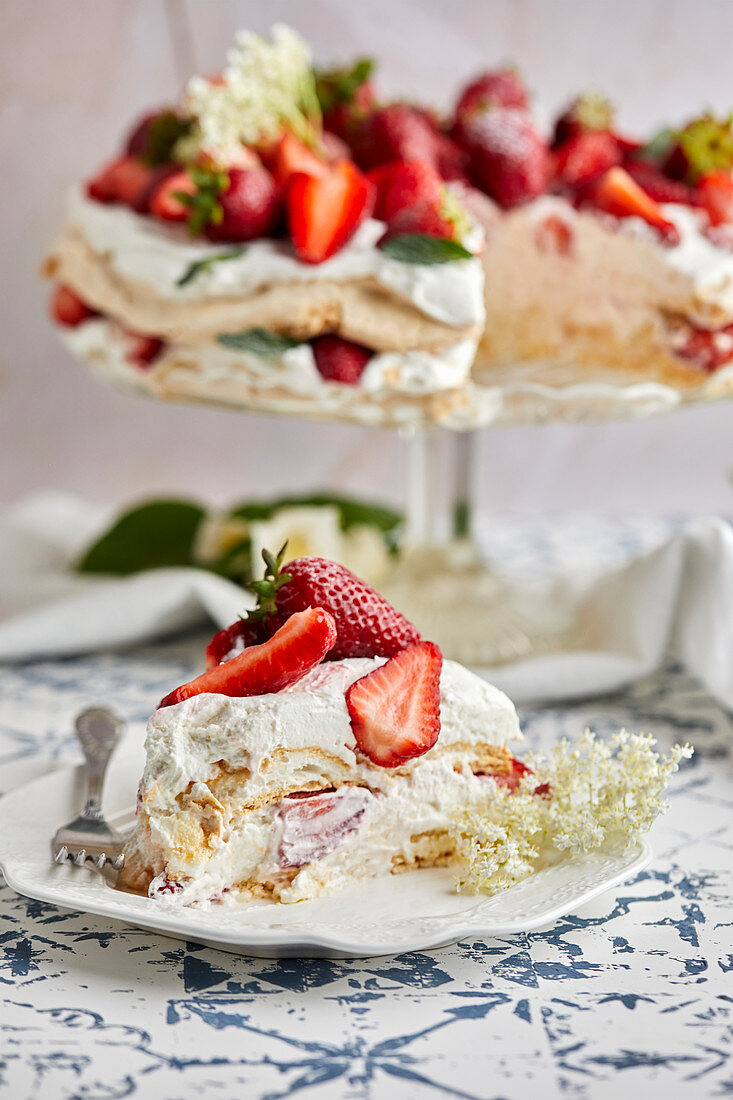 Pavlova cake with fresh strawberries garnished with fresh mint leaves and elderflower