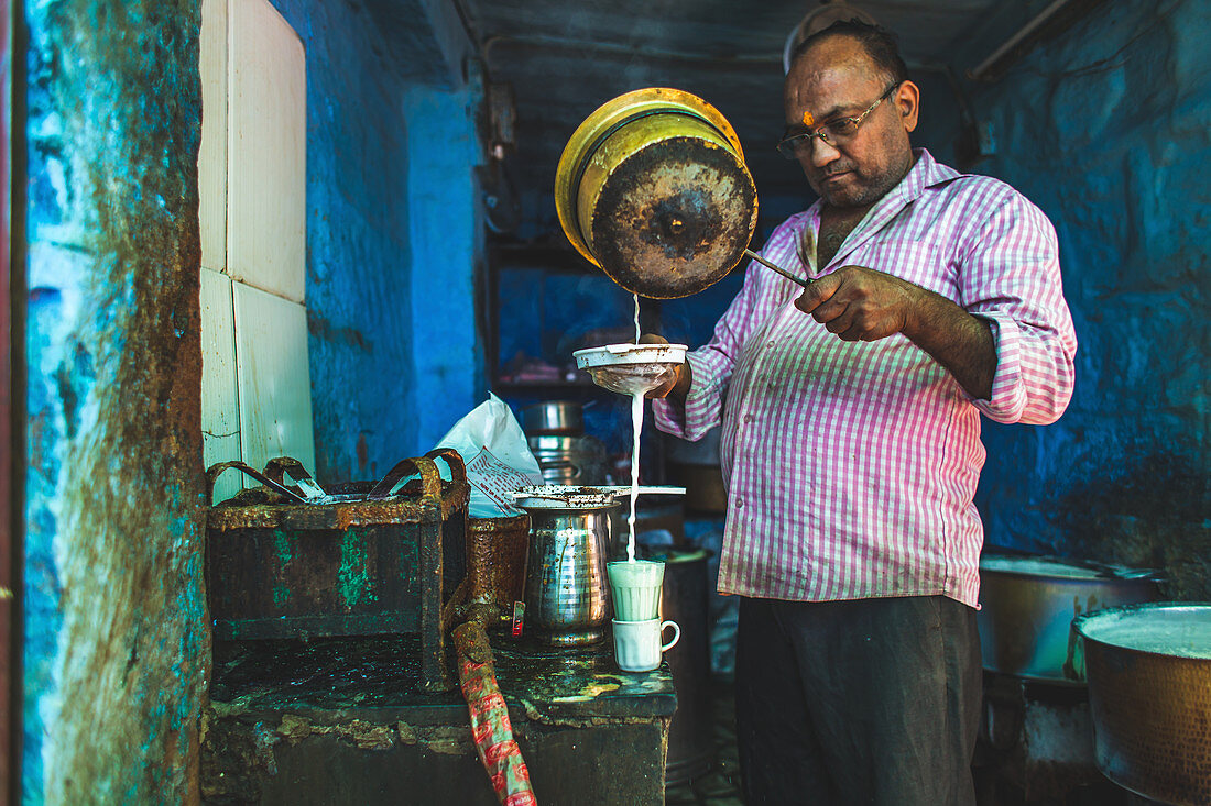 A man making a turmeric chai latte in a street kitchen (India)