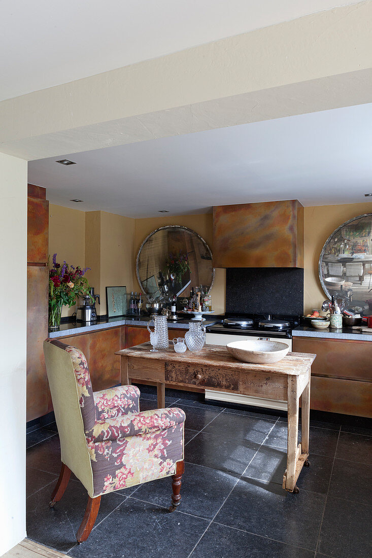 Armchair at old wooden table in kitchen with rusty cabinets