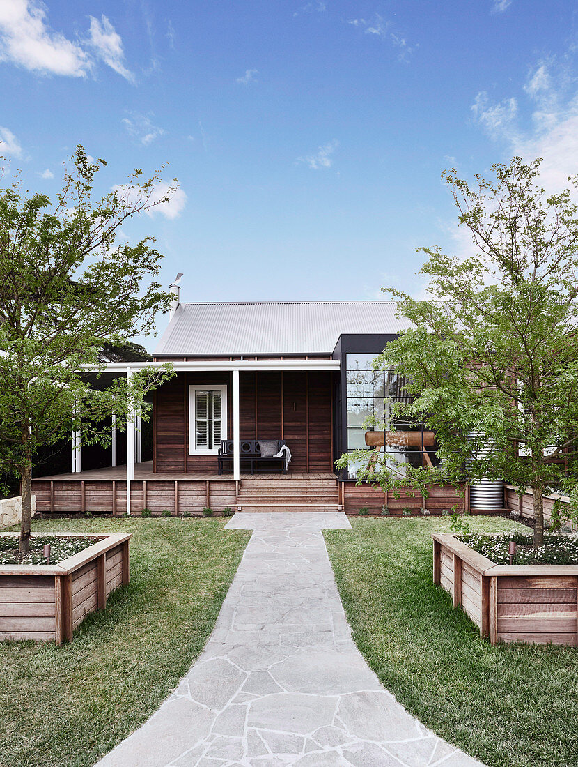 Path with flagstones through the garden to the wooden house under a blue sky