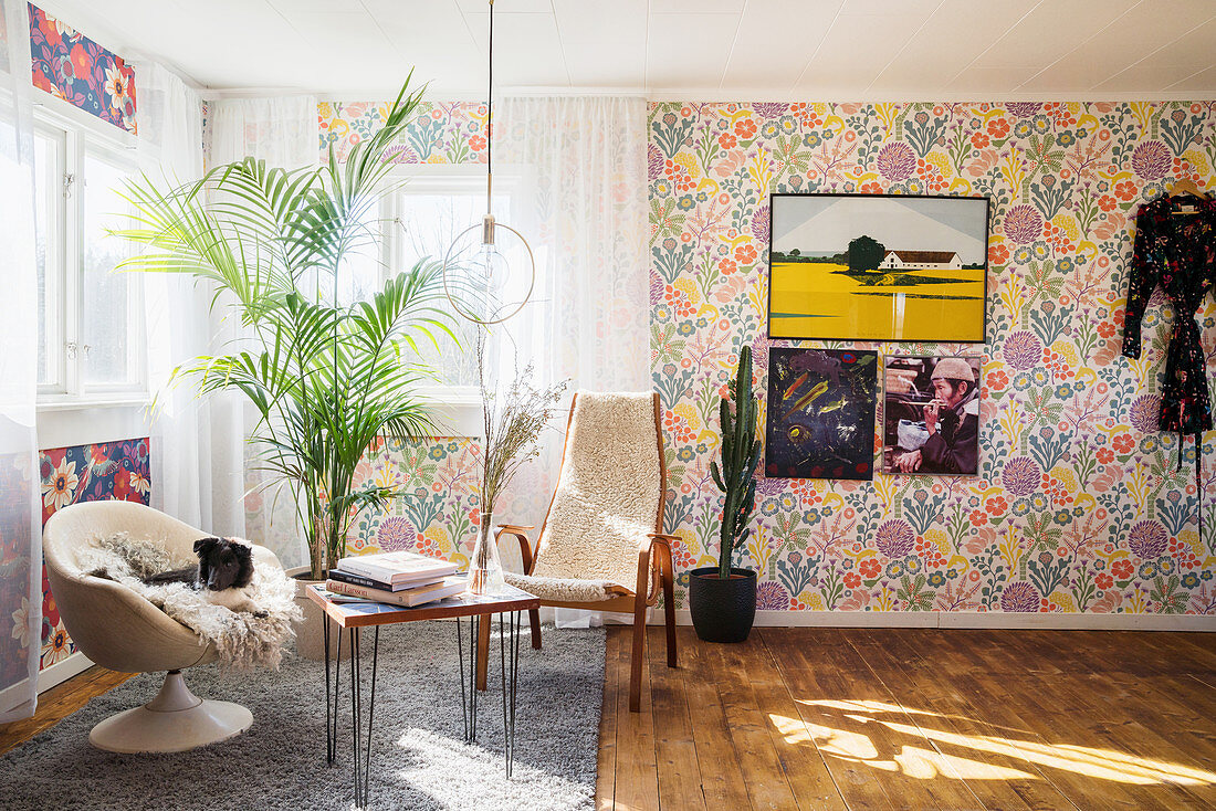 Retro armchairs and floral wallpaper in light-flooded seating area