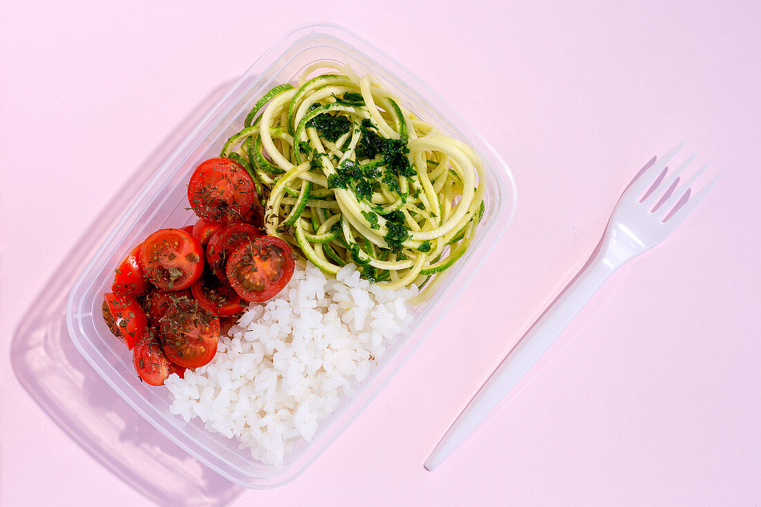 Gesunde Lunchbox mit Tomaten, Zucchininudeln und Reis