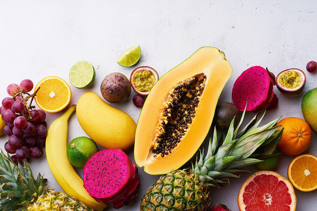 Tropical fruits flat lay with mango, papaya, pitahaya, passion fruit, grapes, limes and pineapples