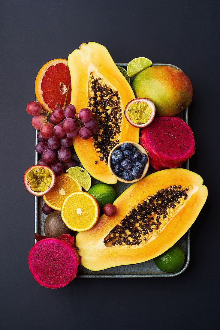 Tropical fruits flat lay with mango, papaya, pitahaya, passion fruit, grapes, limes and pineapples