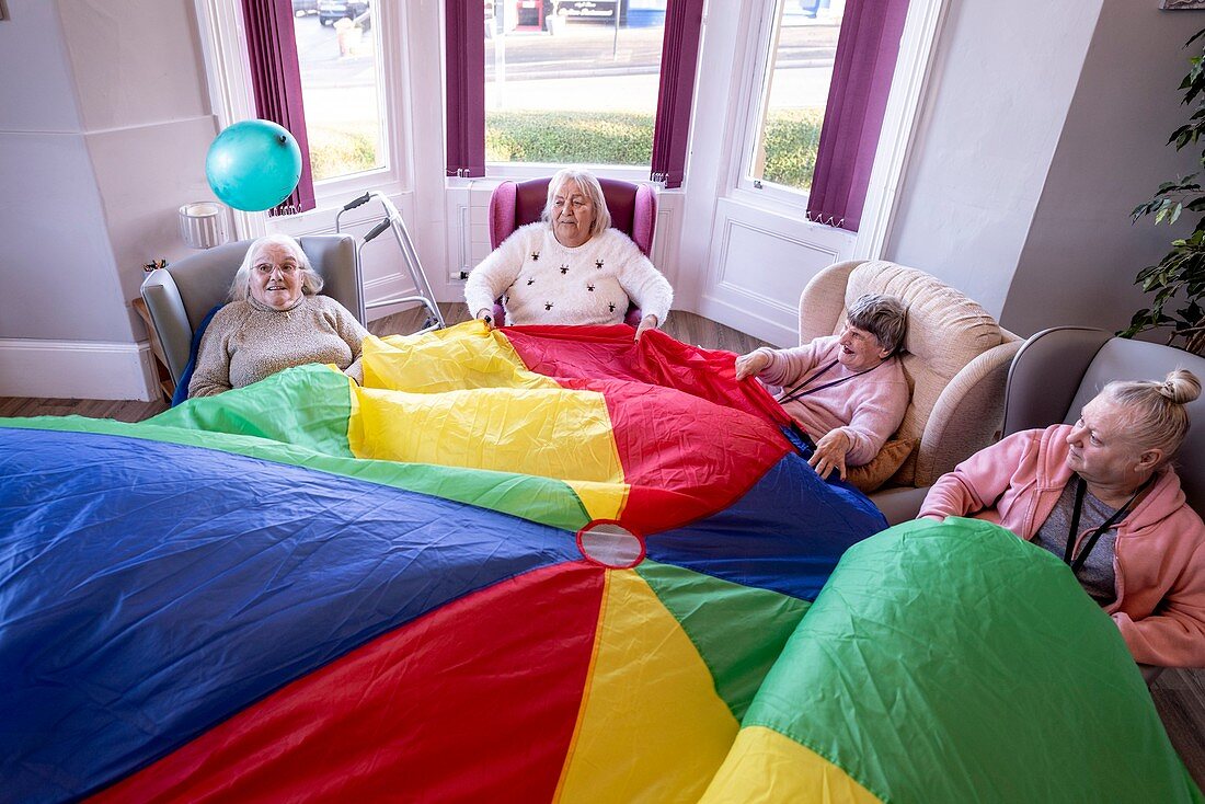 Care home residents in activity with balloon and parachute