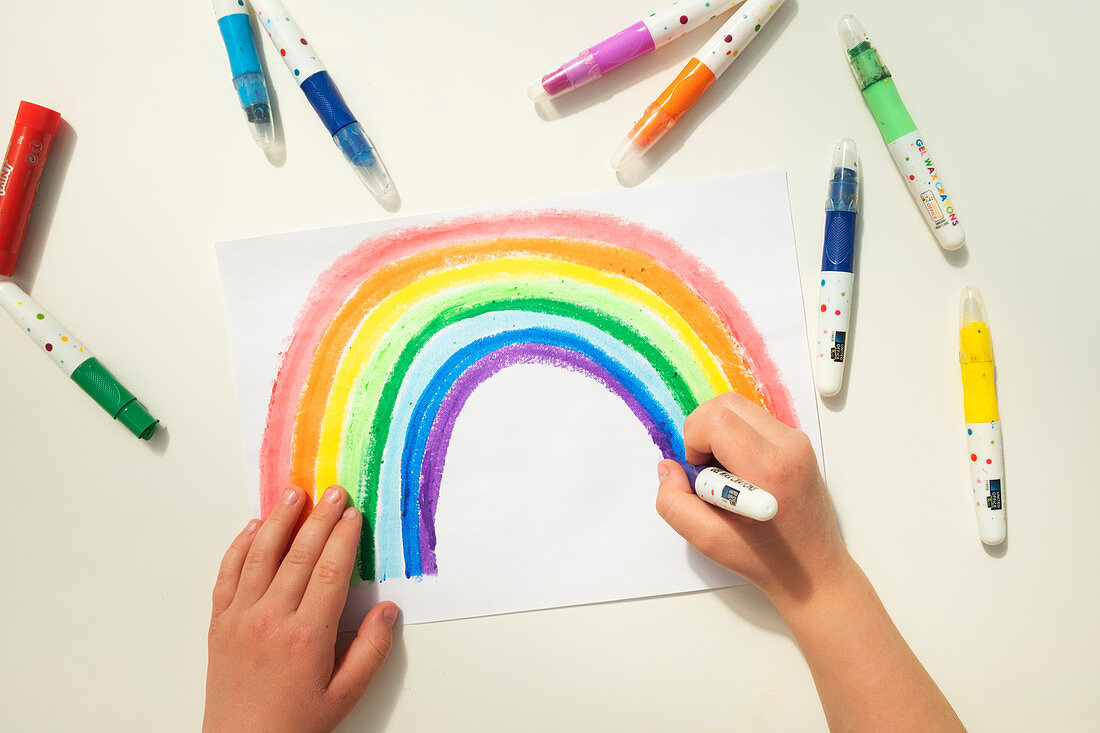 Boy colouring in a rainbow