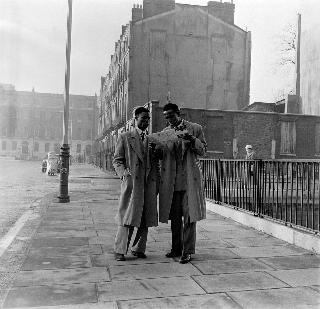 Two Afro-Caribbean men reading a map in the street, London.