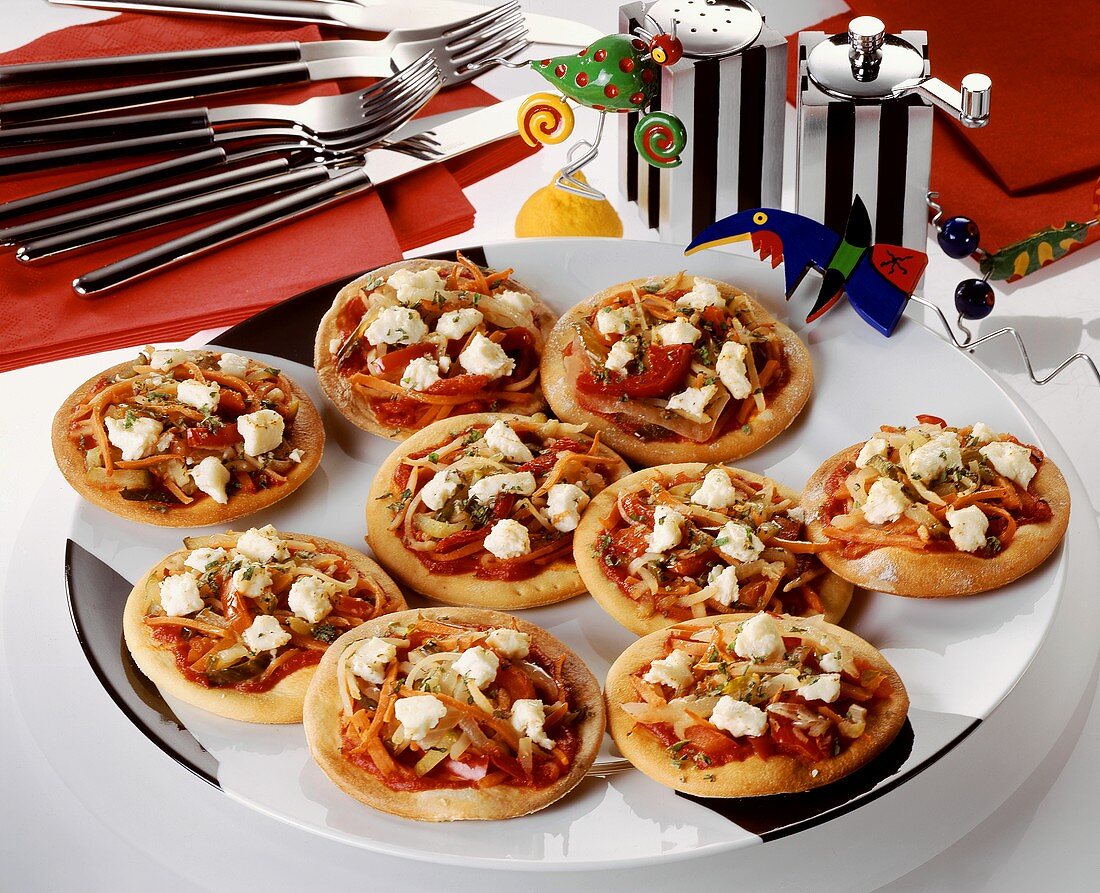 Mini-pizzas with vegetables & sheep's cheese as party snacks