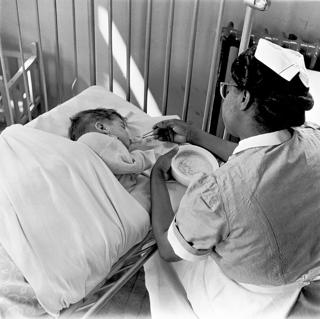 Nurse feeding a child, London