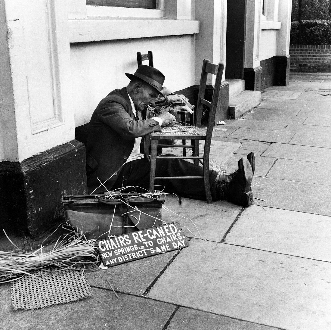 Man mending a chair on an East End street, London, 1950s