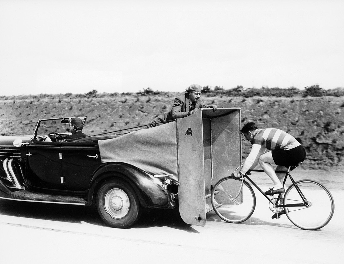 Cyclist training behind an Auburn car, c1935