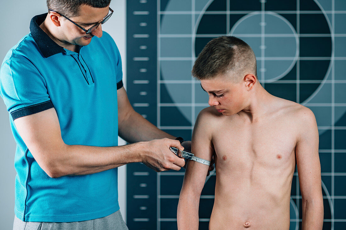 Physical therapist measuring teenage boy's arm