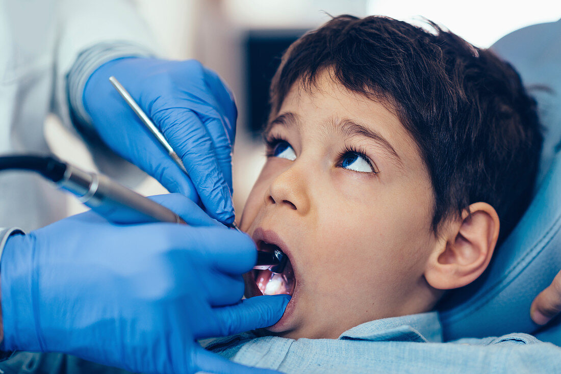 Dentist drilling young boy's tooth